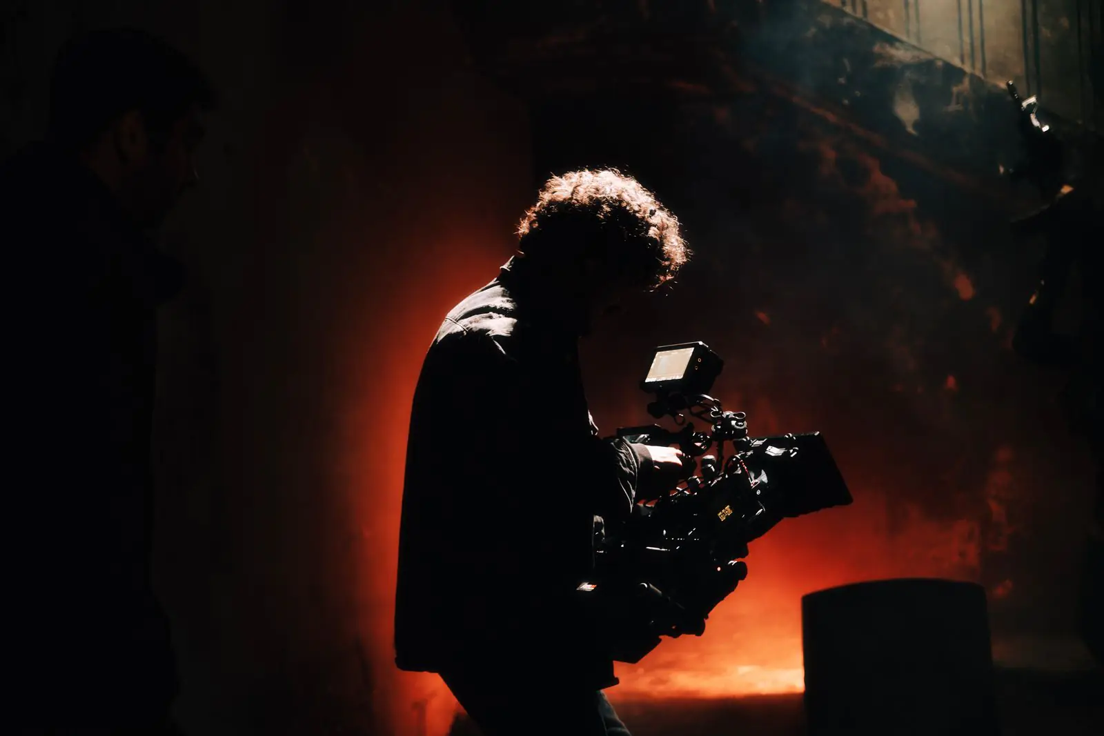 Camarógrafo grabando en un set con iluminación cálida y tenue